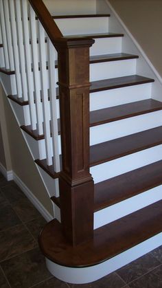 the stairs are made of wood and have white balustiers on them, along with brown tile flooring