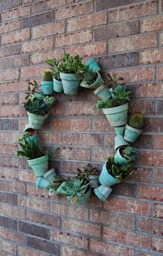 a wreath made out of pots filled with succulents on a brick wall