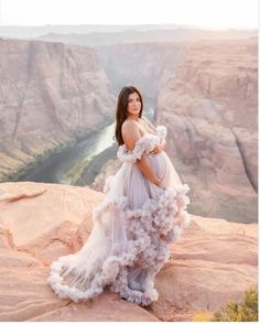 a woman in a dress standing on top of a cliff