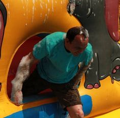 a man climbing up the side of an inflatable animal slide at a carnival