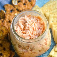 crackers and dip in a jar on a blue tablecloth with other food items