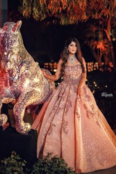 a woman in a pink dress standing next to a statue of a horse and elephant