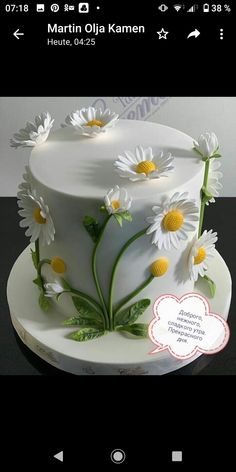 a white cake decorated with daisies and leaves