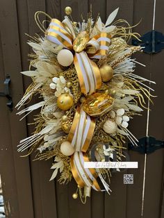 a wreath with gold and white ornaments hanging on a door