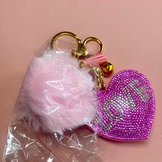 a pink heart shaped keychain sitting on top of a plastic bag