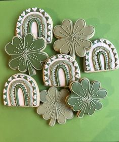 four decorated cookies in the shape of shamrocks and horseshoes on a green background