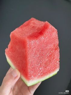 a hand holding a piece of watermelon