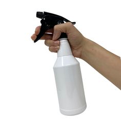 a hand holding a white spray bottle with black handle