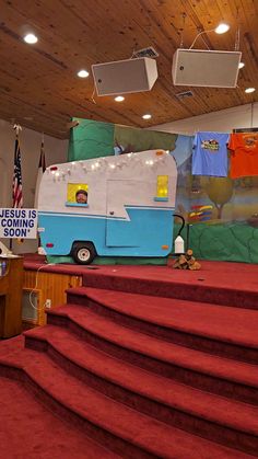 the stage is set up for an event with red carpet and steps leading to a blue camper