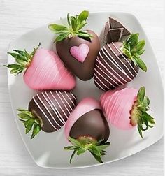 chocolate covered strawberries arranged in a heart shape on a white plate with green leaves