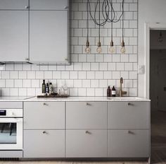 a kitchen with stainless steel cabinets and white subway tile backsplash, an oven and sink