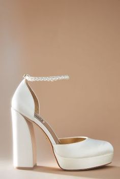 a pair of white high heeled shoes sitting on top of a table