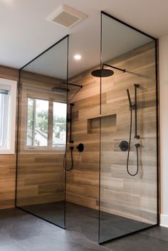 a walk in shower sitting next to a window on top of a wooden wall and floor