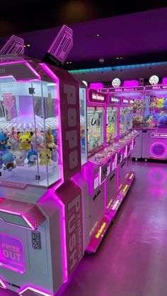 a row of claw vending machines with stuffed animals on them and neon lights in the background