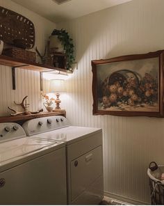 a washer and dryer sitting in a room next to a wall with pictures on it