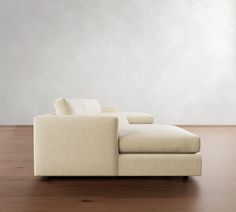 a white couch sitting on top of a wooden floor next to a wall and window