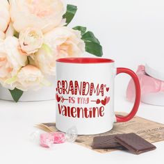 a red and white coffee mug sitting on top of a table next to some candy