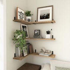 three wooden shelves with books and pictures on them in the corner of a living room