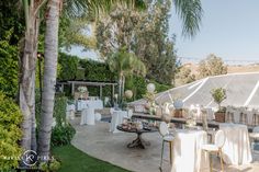 an outdoor dining area with tables and chairs set up for a formal function, surrounded by palm trees