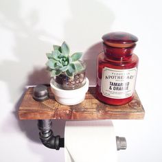 a jar of jam sitting on top of a wooden shelf next to a toilet paper roll