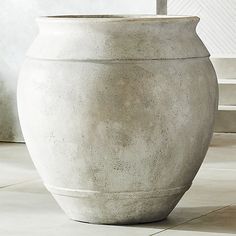 a large white vase sitting on top of a tiled floor