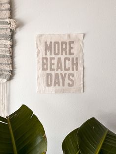 a white wall with a sign that says more beach days on it and some plants