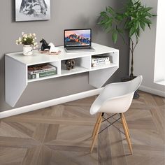 a laptop computer sitting on top of a white desk next to a potted plant