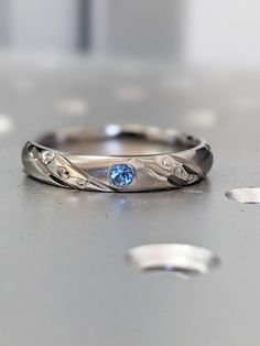 a silver ring with a blue stone in the center on top of a metal surface