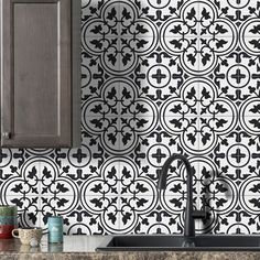 a black and white tile backsplash in a kitchen with wooden cabinets, coffee mugs on the counter