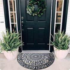 two large planters are sitting in front of a door with a wreath on it