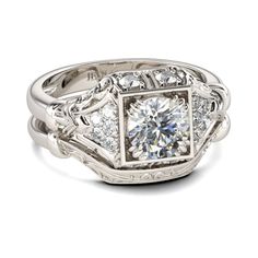 a white gold engagement ring with diamonds on the sides and an intricate design around it