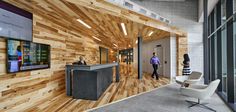 an office with wood paneling and two people walking in front of the reception desk