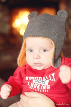 a baby wearing a bear hat while sitting on someone's lap