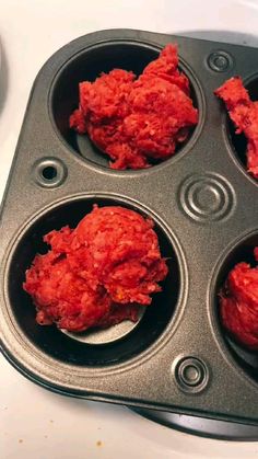 four muffin tins filled with red meat sitting on top of a white counter