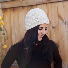 a woman with long black hair wearing a white knitted hat