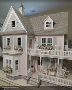 a pink doll house with white porches and flowers on the windows sills