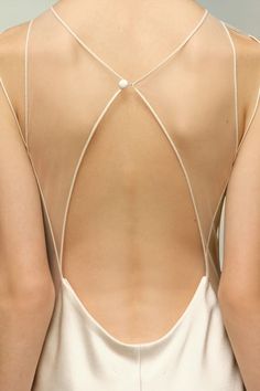 the back of a woman's white dress with a cross - back design on it