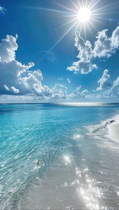 the sun shines brightly over an ocean beach with clear blue water and white clouds