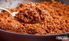 a spoon full of ground meat in a pan