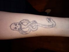 a person with a tattoo on their arm that has two skulls and an octopus in it