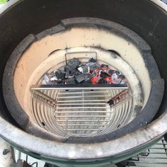 a large metal basket filled with lots of trash sitting on top of a table next to a fire pit