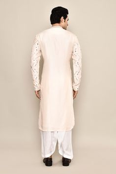 Blush cream kurta featuring mirror embroidery in the front and sleeves. Paired with a white salwar. - Aza Fashions Festive White Kurta With Embroidered Sleeves, White Embroidered Unstitched Kurta, White Kurta With Embroidered Sleeves, Eid White Kurta With Embroidered Sleeves, White Chanderi Sherwani With Mirror Work, Festive Sherwani With Embroidered Sleeves For Wedding, Wedding Traditional Wear With Embroidered Sleeves In Chanderi, Wedding Traditional Wear With Embroidered Sleeves, Chanderi Traditional Wear With Embroidered Sleeves For Wedding