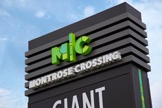 a large sign that says montrose crossing and giant letters on the side of it in front of a cloudy blue sky