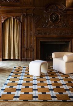 a living room with two white chairs and a checkered rug in front of a fireplace