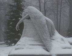 a statue is covered in snow with trees in the backgrouds behind it