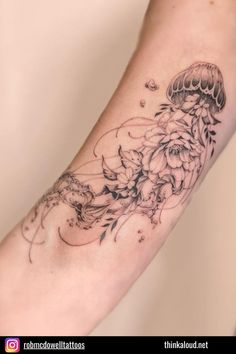 a black and white photo of a jellyfish tattoo on the left arm with flowers