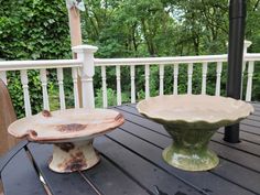 two dishes sitting on top of a wooden table next to each other in front of trees