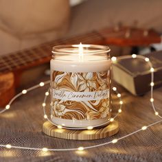 a lit candle sitting on top of a table next to a string of lights and a guitar