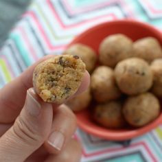 a hand holding a cookie in front of a bowl of cookies