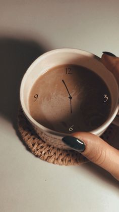 a woman's hand holding a coffee cup with a clock on it